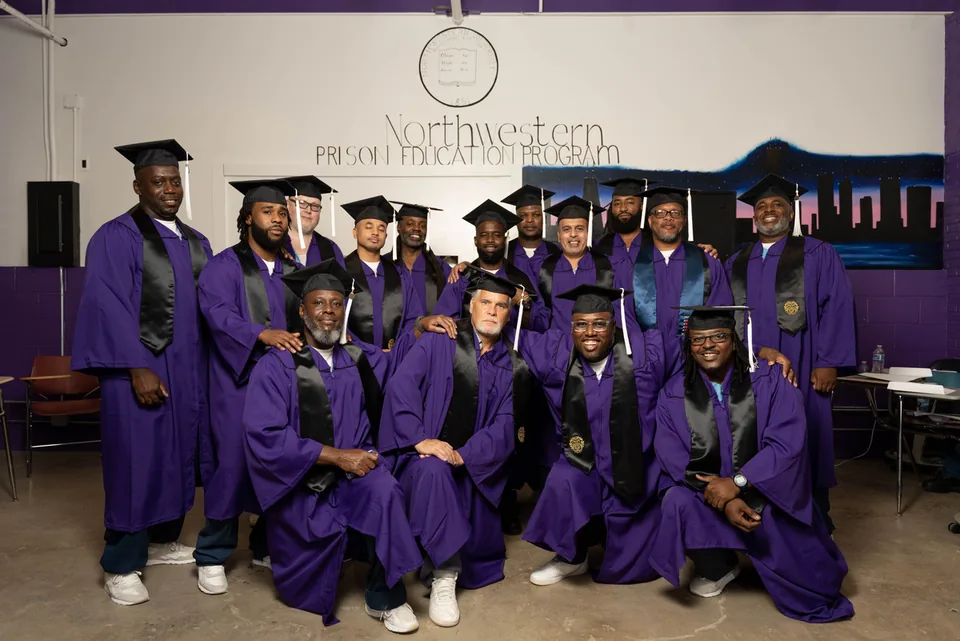 A group photo of graduates in purple gowns and mortarboards in front of a Northwestern Prison Education Program mural.