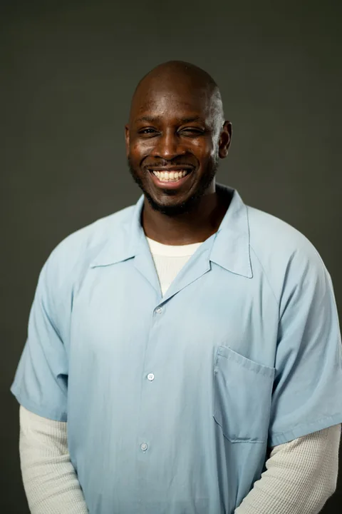 Studio portrait of Michael Bradley, a member of Cohort 5, in a light blue button-up shirt against a dark gray backdrop.