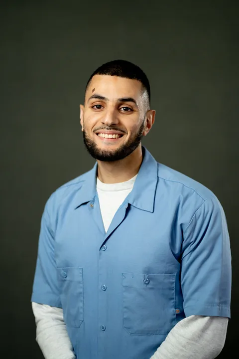 Studio portrait of Mohammad Salahat, a member of Cohort 5, in a light blue button-up shirt against a dark gray backdrop.