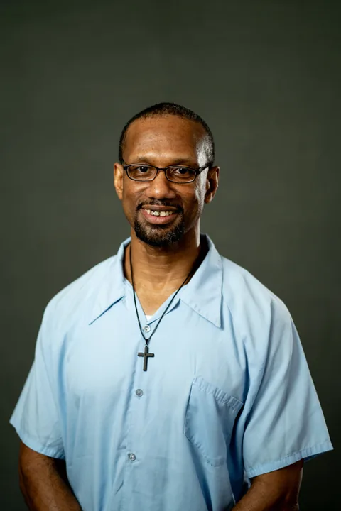 Studio portrait of Patrick Comi, a member of Cohort 5, in a light blue button-up shirt against a dark gray backdrop.