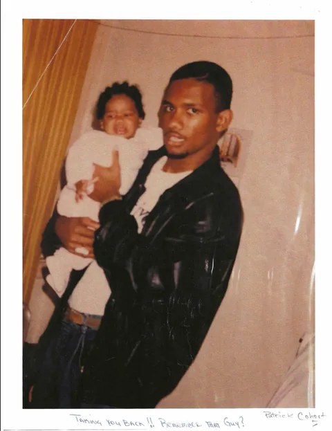 Older snapshot of a man holding a baby in a white outfit.