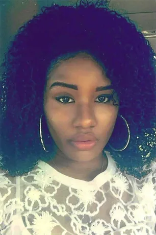 Selfie-style photo of a young woman with curly hair and large hoop earrings.