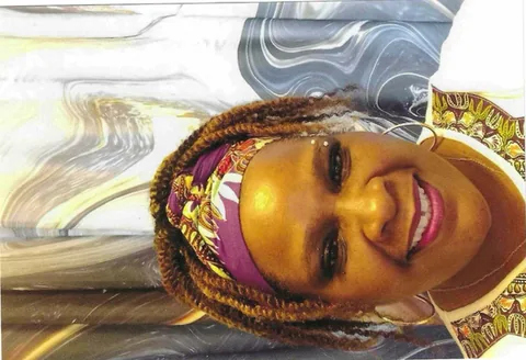 Close-up photo of a smiling woman wearing a colorful patterned headband and top.